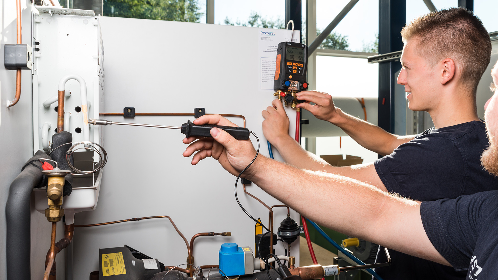 Zwei INSTATEC Techniker bei der Messung an einer Kälteanlage mit digitalem Monteurhilfe-Manometer